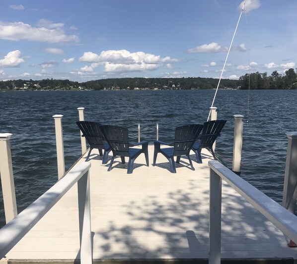 A wooden dock with two chairs facing a body of water.