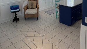 Eine moderne Küche mit einer blauen Kochinsel, einem Korbstuhl und einem kleinen Tisch mit blauer Sitzauflage.
