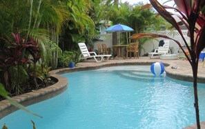A swimming pool with a blue and white beach ball, surrounded by palm trees and white lounge chairs. - Family-Friendly Anna Maria Island 3BR • Walk to Beach & Dining • Private Pool (Holmes Beach)