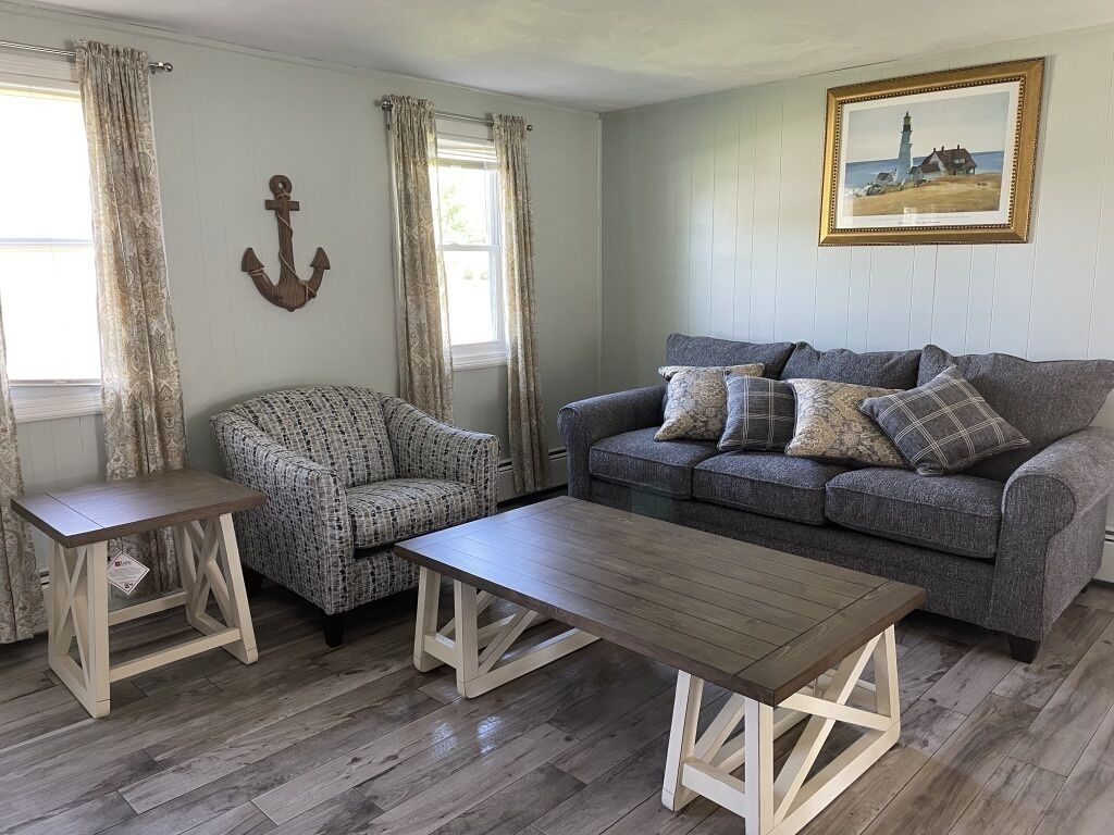 A living room with a grey sofa, patterned armchair, and a wooden coffee table.