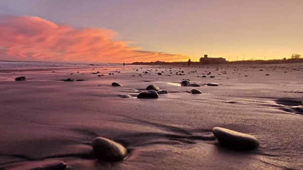 A beach with scattered rocks and a distant structure. - Walk to Beach with with central AC! (Narragansett)