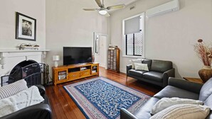 A living room with a fireplace, a television, a sofa, a coffee table, and a blue patterned rug.