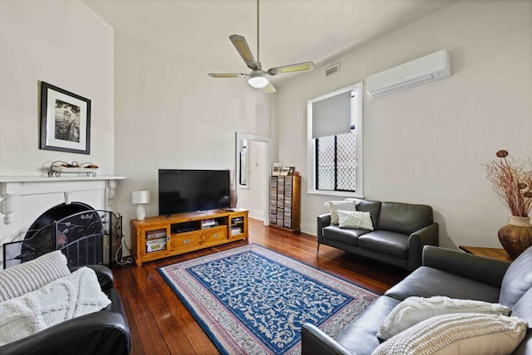 A living room with a fireplace, a television, a sofa, a coffee table, and a blue patterned rug.