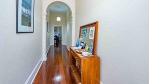 A hallway with a wooden bench, framed pictures, and a mirror on the wall. - Geraldton City Stay Cottage on Sanford (Geraldton)