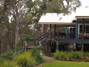 A building with a covered outdoor area, a staircase, and a view of the surrounding trees.