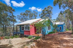 A row of cabins with a dirt path between them, surrounded by trees.