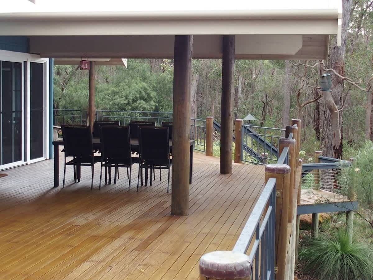 Une terrasse en bois avec des sièges extérieurs et un escalier menant à une zone abritée.