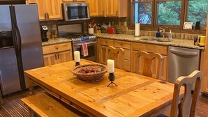 Una cocina de madera con una isla central, armarios de madera, un refrigerador, un microondas y un fregadero.
