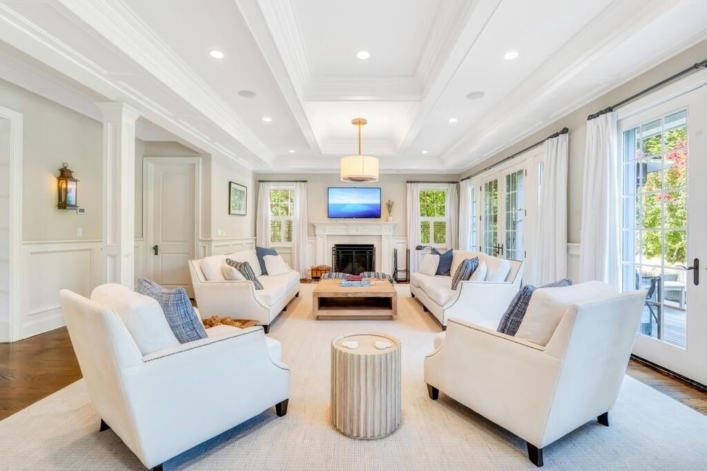 A spacious living room with white sofas, a central coffee table, and a fireplace.