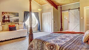 A bedroom with a four-poster bed, a sofa, a painting, and a large window with curtains.