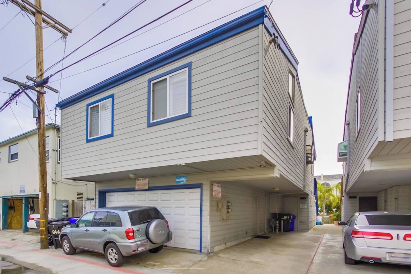 A two-story building with a garage, parked cars, and visible utility poles.