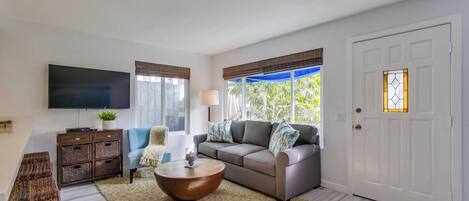 A living room with a sofa, coffee table, TV, and a door with a window.