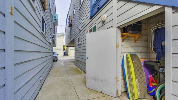A narrow alleyway between buildings with a car parked at the end. - MB Bungalow steps to the bay for pets with bikes (San Diego)