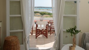 Una habitación con vista a la playa, una cesta de mimbre, una mesita con un florero y un sofá.