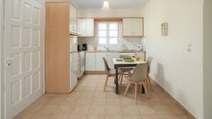 Cocina compacta con zona de comedor, que incluye una puerta blanca, armarios de madera, un ventanal y una lámpara.