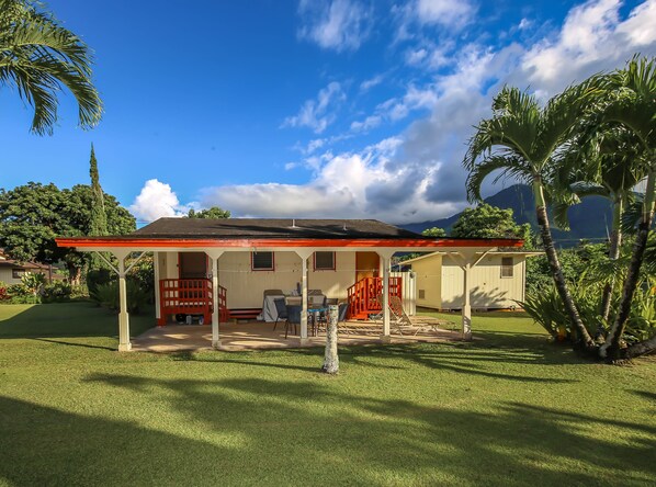 A house with a covered porch, a lawn, and palm trees. - Malolo Cottage - a studio/1ba home near the beach in Hanalei (Hanalei)