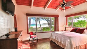 A bedroom with a bed, a chair, a desk, and a window with a view of the beach. - Ka Nani, steps from the sand! The center of Hanalei Bay. Best $ on the bay. (Hanalei)