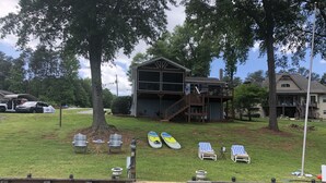 A lakeside property with a dock, lounge chairs, kayaks, and a large house with a balcony. - Lake House with amazing lake views (Inman)