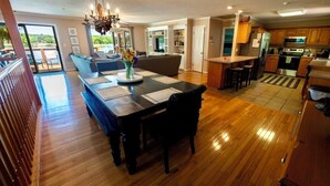 A spacious living area with a wooden dining table, a chandelier, and a view of the outdoors. - Lake House with amazing lake views (Inman)
