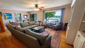 A cozy living room with a sofa, coffee table, and chairs. There is a large window with a view of the outdoors. - Lake House with amazing lake views (Inman)