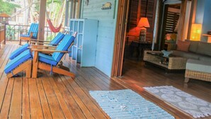 Una terraza de madera con sillones azules, un sofá de mimbre y una pequeña mesa.