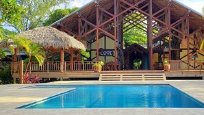 Un resort con piscina, terraza de madera y una estructura de techo de paja con la etiqueta 'COVE'.