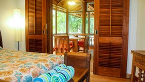 Una habitación con cama, una mesa de madera y sillas. Hay una ventana con vista a zonas verdes.