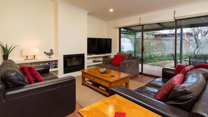 A modern living room with a fireplace, a television, and a large sliding glass door leading to a patio. - Classic on George- clean, comfortable and pet friendly! - Classic heritage home with four bedrooms (Albury)