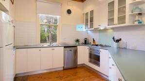 A modern kitchen with white cabinets, a wooden floor, and a window with a view of trees. - Classic on George- clean, comfortable and pet friendly! - Classic heritage home with four bedrooms (Albury)