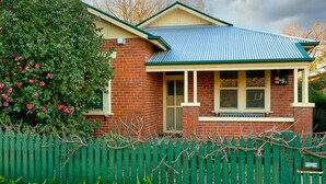 A two-story brick house with a green metal roof and a picket fence. - Classic on George- clean, comfortable and pet friendly! - Classic heritage home with four bedrooms (Albury)