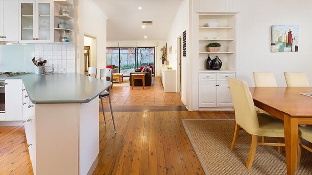 A spacious kitchen with wooden flooring, white cabinetry, and a dining area with a wooden table and chairs. - Classic on George- clean, comfortable and pet friendly! - Classic heritage home with four bedrooms (Albury)