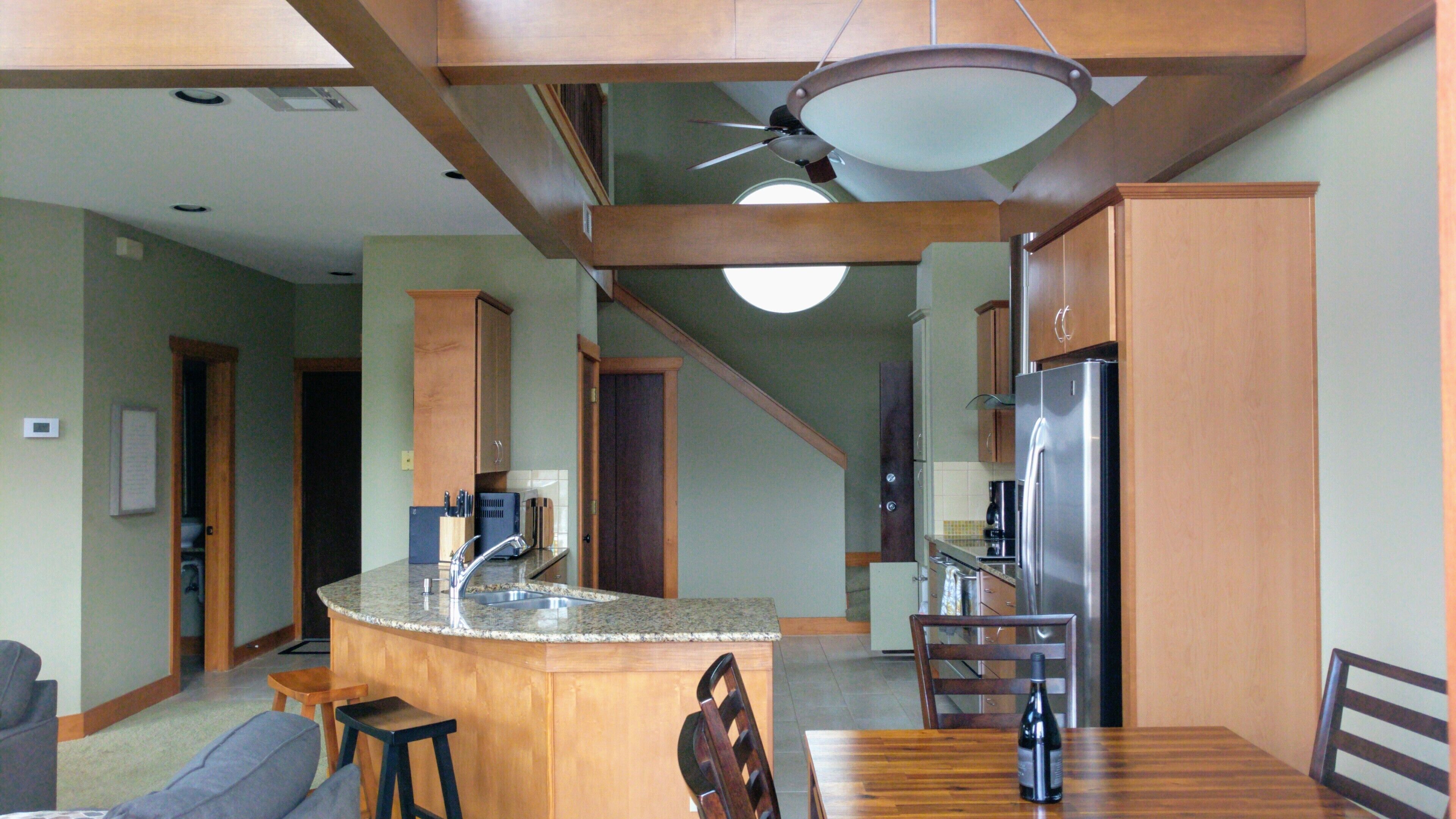A spacious kitchen with a central island, wooden cabinets, and a stainless steel refrigerator.