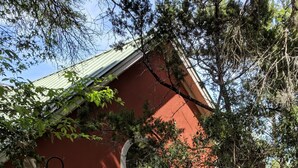Ein Holzzaun mit einer Hausnummer, eine kleine Veranda mit einem grünen Dach und ein rotes Gebäude im Hintergrund.