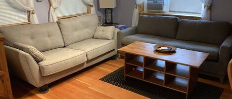 A cozy living room with two sofas, a wooden coffee table, and a small side table.
