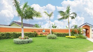 A landscaped area with a sign for "Drax Hall Manor" and palm trees.