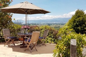 An outdoor patio with a table and chairs, an umbrella, and a view of the countryside. - Golden Hills Farm Cottage, Stunning Views and a Swimming Pool (Richmond)