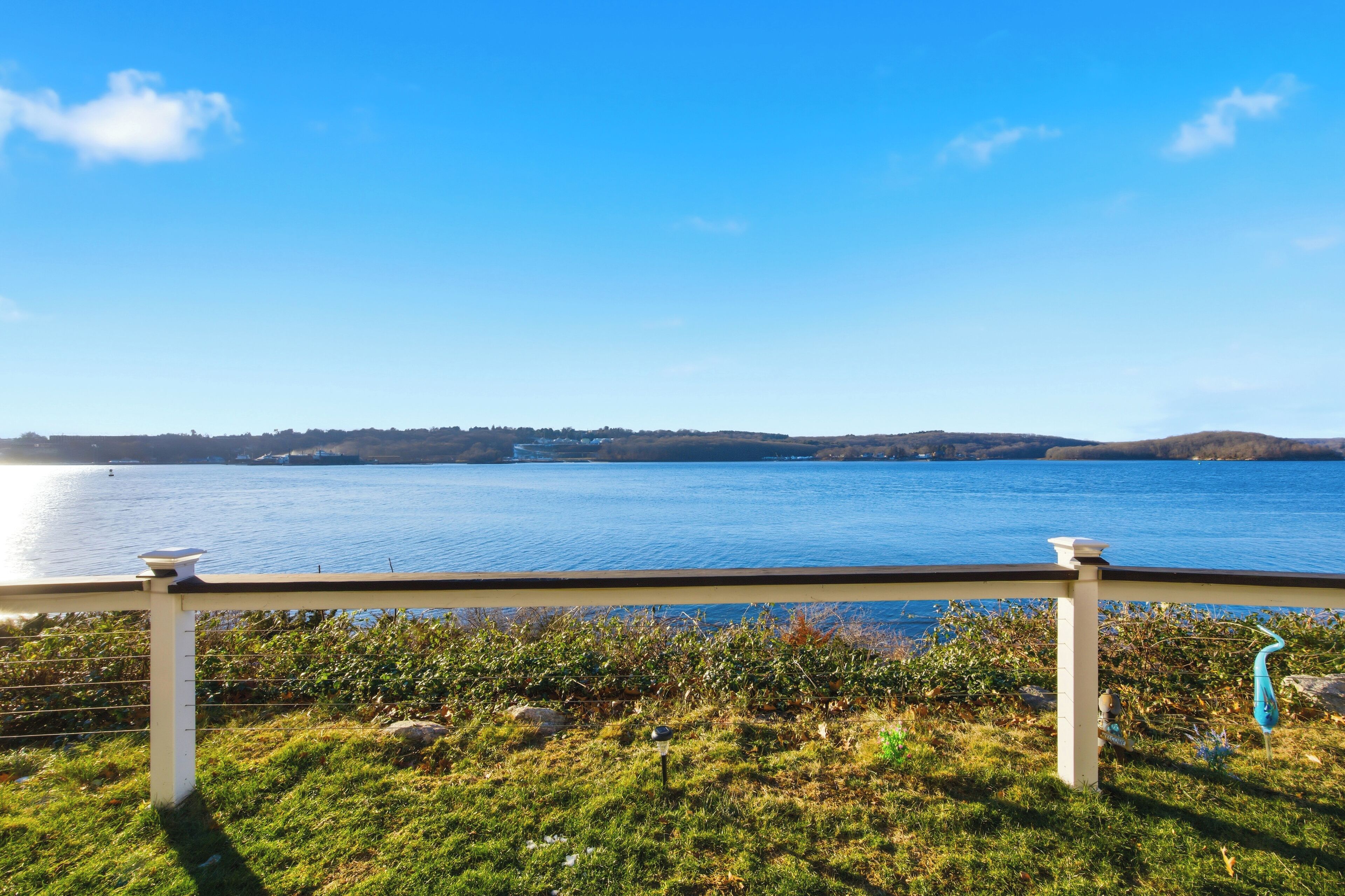 A view of a lake with a white railing in the foreground.