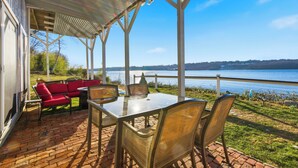A covered patio with a table and chairs, overlooking a body of water.