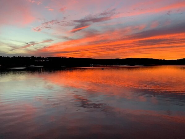 A calm lake at sunset with a reflection of the sky. - Comfy Waterfront Walkout! Enjoy your own private terrace overlooking the Thames! (Groton)