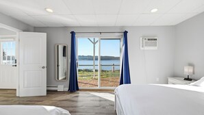 A hotel room with a large sliding glass door leading to a balcony with a view of the sea.