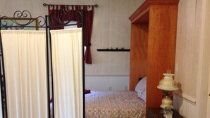 A bedroom with a bed, a nightstand, a lamp, and a window with curtains. - Farm cottage for football/graduation weekends. (Pennsylvania Furnace)