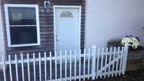 A house with a white picket fence, a closed white door, and a window with blinds. - Farm cottage for football/graduation weekends. (Pennsylvania Furnace)