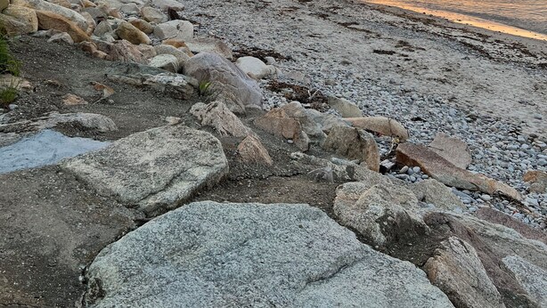 Ein felsiger Strand mit Sonnenuntergang im Hintergrund.
