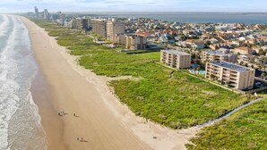 A coastal cityscape with a beach, residential buildings, and a bridge in the distance. - SPI Beach House Gateaway 1-504 (South Padre Island)