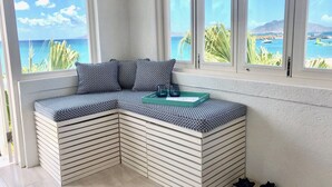 A corner seating area with a patterned cushion, a tray, and a view of the sea and mountains. - Unique Beachfront Suite, private with an amazing view w option of 2 more rooms. (Cades Bay)