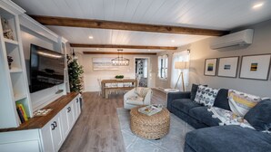A modern living room with a wooden ceiling, a TV, a dining area, and a cozy seating area. - Salty but Sweet - 3 min walk to Beach - Newly Renovated - Video! (Wells)