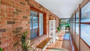 A corridor with brick walls, large windows, and a wooden bench. - Hat Hill Hideaway Amazing Valley Views (BLACKHEATH)