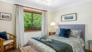 A bedroom with a bed, a chair, a nightstand, and a window with curtains. - Hat Hill Hideaway Amazing Valley Views (BLACKHEATH)