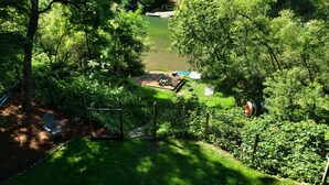 Un jardín exuberante con una terraza de madera, una hamaca y una piscina pequeña.