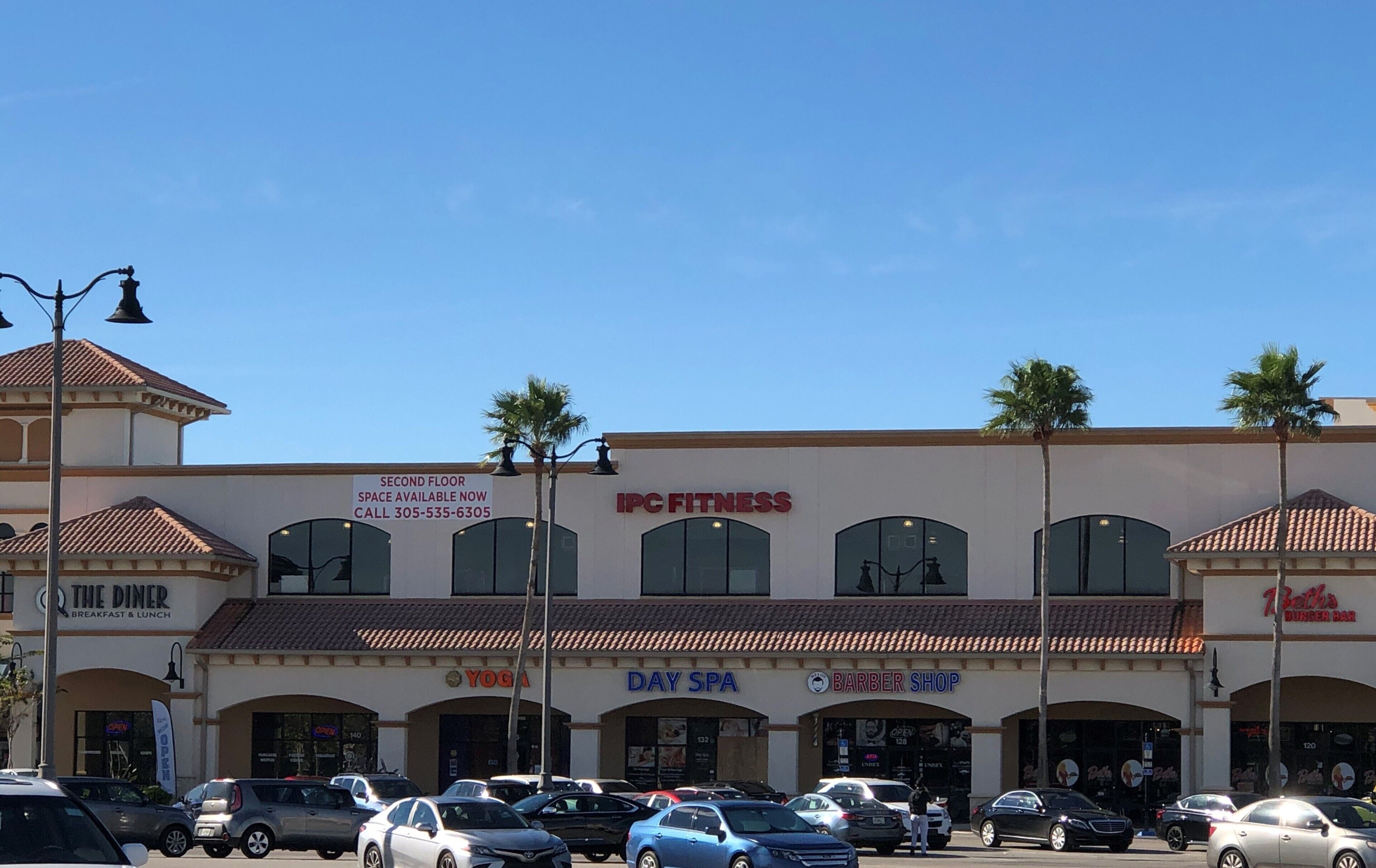 A commercial building with multiple storefronts including a fitness center, yoga studio, spa, and barber shop.